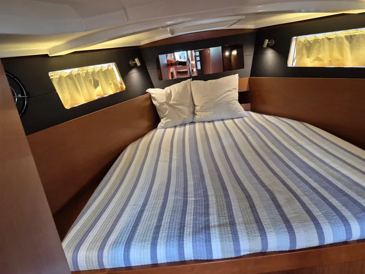 Wanderer Yacht Photos Pics Cozy cabin interior of 2019 Beneteau Oceanis 41.1 with striped bedding and soft lighting.