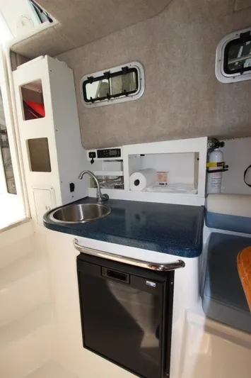 No Name Yacht Photos Pics Compact kitchenette in 2015 True World Marine TE 289 boat with sink, counter, and mini fridge.