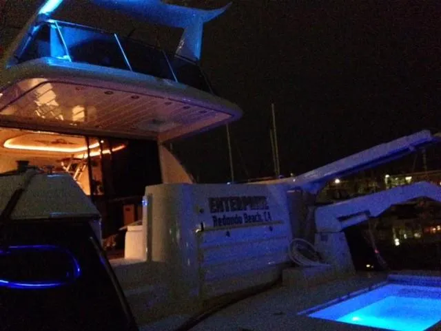 The Enterprise Yacht Photos Pics Sunseeker MANHATTAN 1995 yacht with blue lighting at night, docked at a marina.
