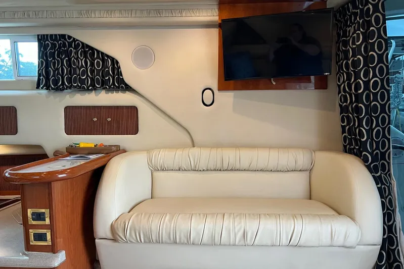  Yacht Photos Pics Interior of 2000 Sea Ray 400 Sedan Bridge with sofa, TV, and patterned curtains.