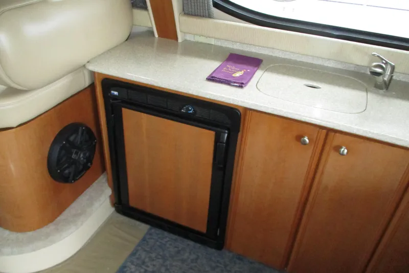 New Lease On Life Yacht Photos Pics 2004 Meridian 340 yacht interior with kitchenette, featuring sink, fridge, and wooden cabinetry.