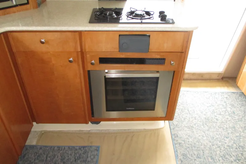 New Lease On Life Yacht Photos Pics 2004 Meridian 340 kitchen with stove and oven, featuring wooden cabinetry and countertop.
