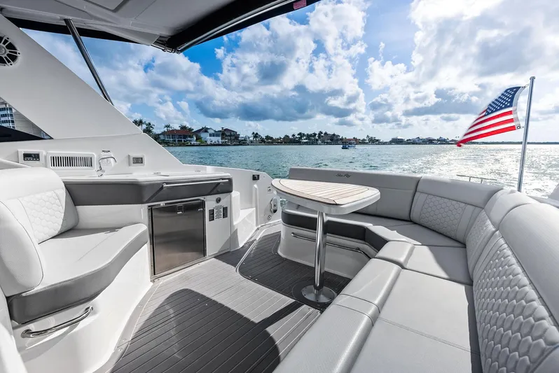 Swelltimes IV Yacht Photos Pics 2022 Sea Ray Sundancer 320 OB yacht interior with seating, table, and American flag on a sunny day.