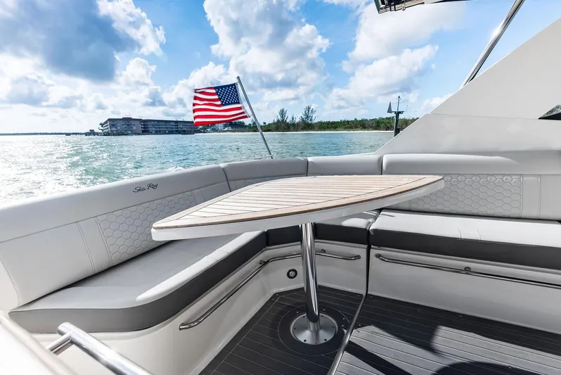Swelltimes IV Yacht Photos Pics 2022 Sea Ray Sundancer 320 OB boat interior with seating and table, American flag in background.