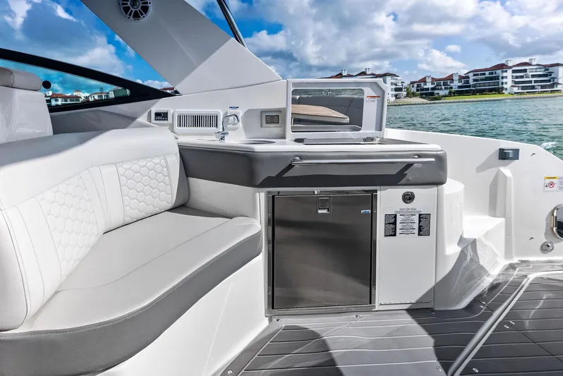 Swelltimes IV Yacht Photos Pics 2022 Sea Ray Sundancer 320 OB interior with seating and kitchenette, overlooking waterfront buildings.