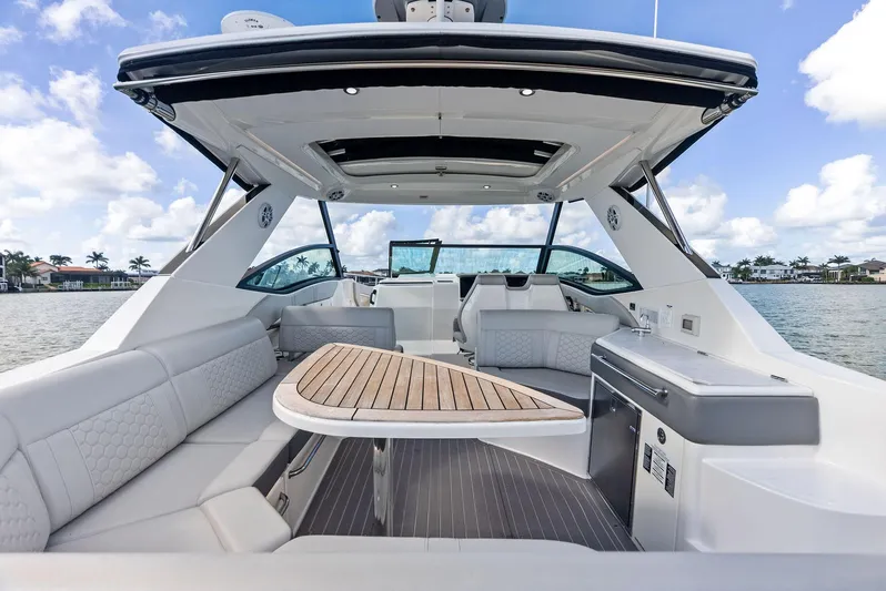 Swelltimes IV Yacht Photos Pics 2022 Sea Ray Sundancer 320 OB boat interior with seating and table, on a sunny day.
