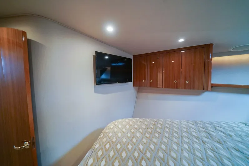 Bad Habits Yacht Photos Pics Interior of 2007 Viking 45 Convertible yacht bedroom with TV and wooden cabinets.