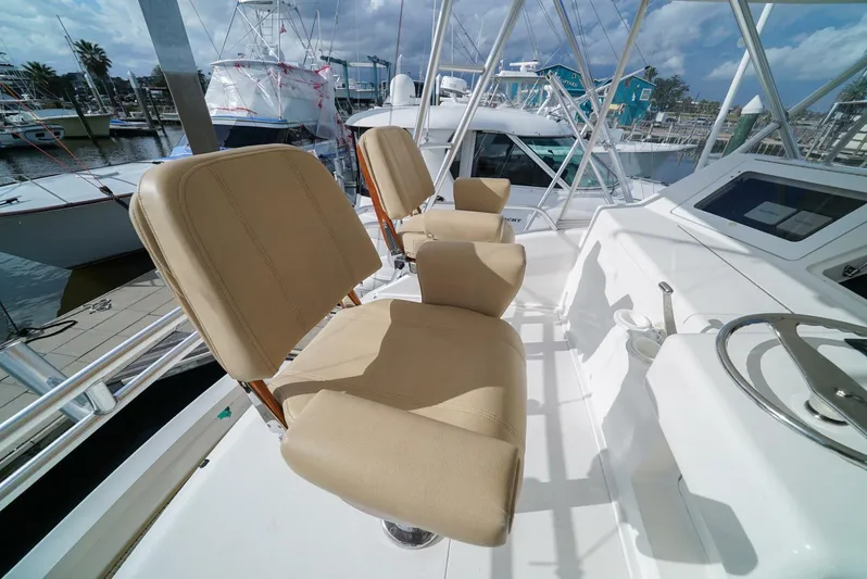 Bad Habits Yacht Photos Pics 2007 Viking 45 Convertible yacht helm with beige captain chairs and marina view.