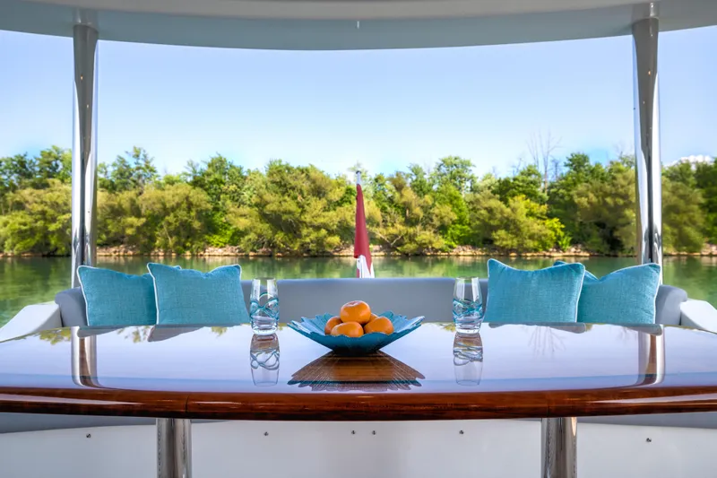 Family Tradition II Yacht Photos Pics Luxurious Neptunus 750FX yacht deck with table, blue cushions, and scenic water view.