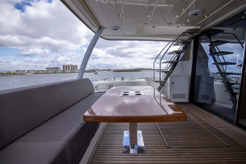 Prestige Worldwide Yacht Photos Pics 2018 Prestige 680 Flybridge yacht with elegant deck seating and table, overlooking serene waters.