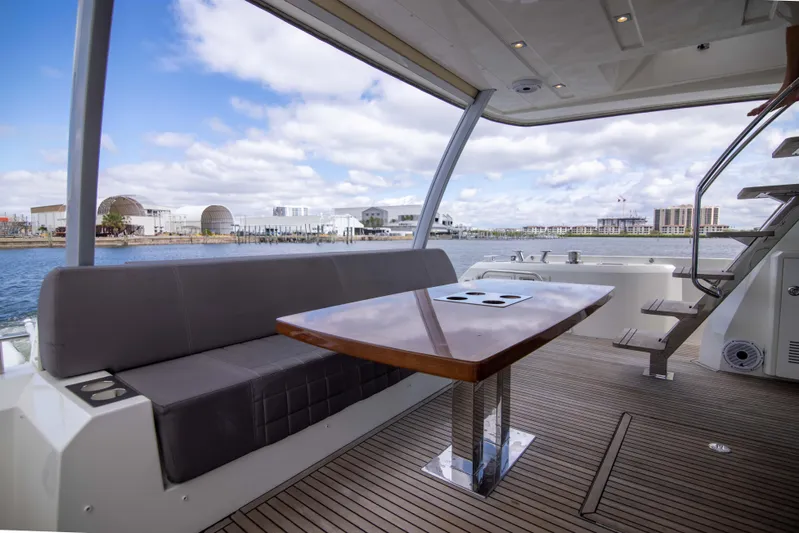Prestige Worldwide Yacht Photos Pics 2018 Prestige 680 Flybridge yacht with elegant seating and table, overlooking a scenic waterfront.