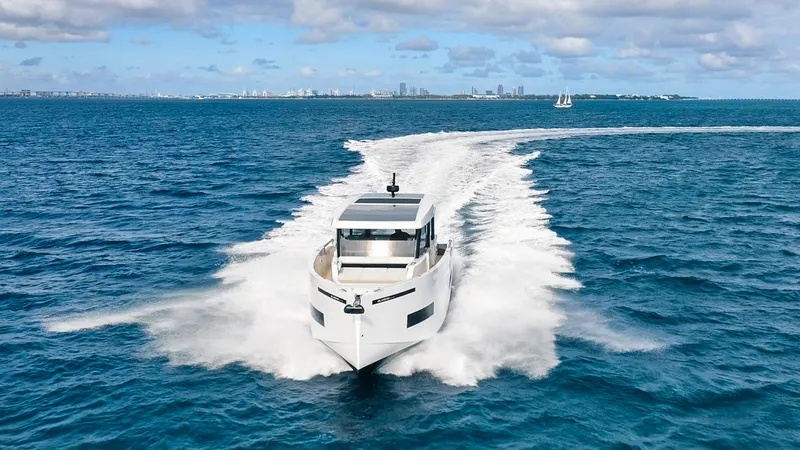 Yacht Photos Pics 2025 De Antonio Yachts D50 Coupé cruising on open sea with city skyline in background.