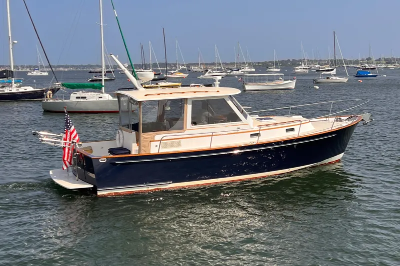 Indigo Yacht Photos Pics 2007 Bruckmann 34e boat on water, surrounded by sailboats, with American flag.