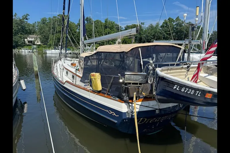 Dreamwalker Yacht Photos Pics 2008 Gozzard 41B sailboat docked in a marina, surrounded by trees and calm water.
