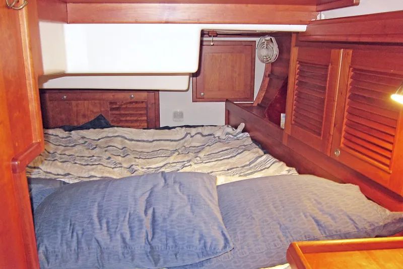 Dreamwalker Yacht Photos Pics Cozy cabin interior of 2008 Gozzard 41B sailboat with wooden furnishings and striped bedding.