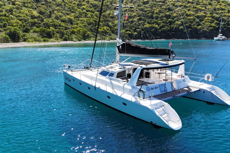 Knot Bad! Yacht Photos Pics 2008 Voyage Yachts 500 catamaran sailing in clear blue waters near a lush green coastline.