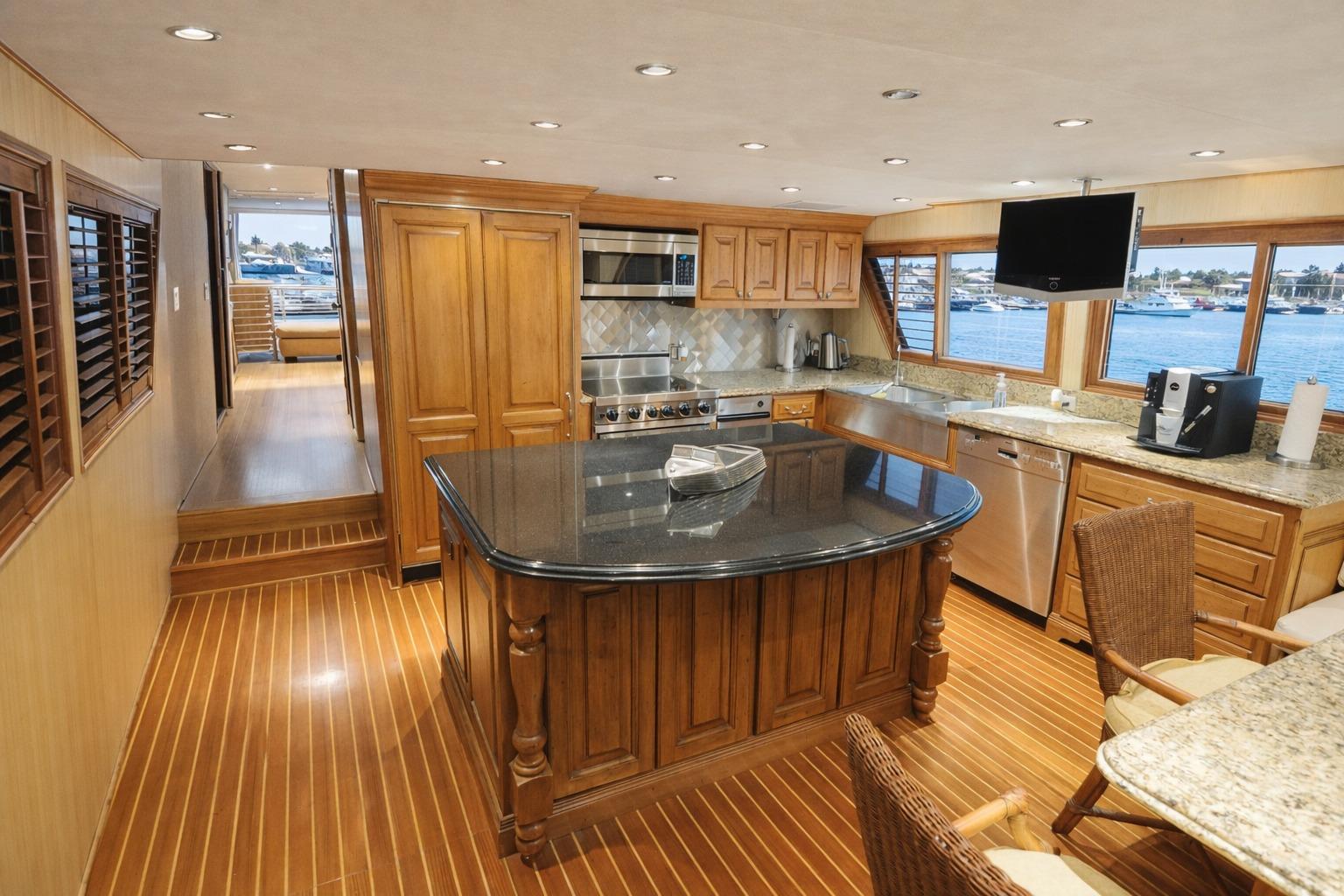 Luxurious 1987 Broward Cockpit Motor Yacht kitchen with wood cabinetry and ocean views.