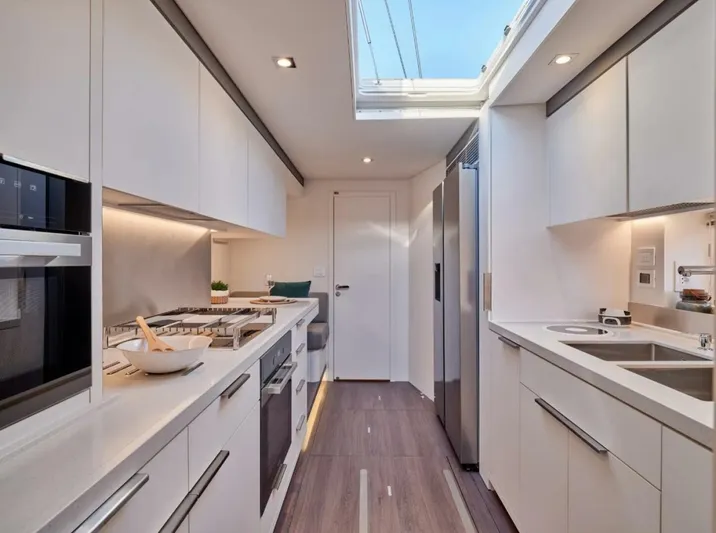 Sicilian Breeze Yacht Photos Pics Modern kitchen interior in 2021 Lagoon Seventy 7 yacht, featuring sleek white cabinetry and stainless steel appliances.