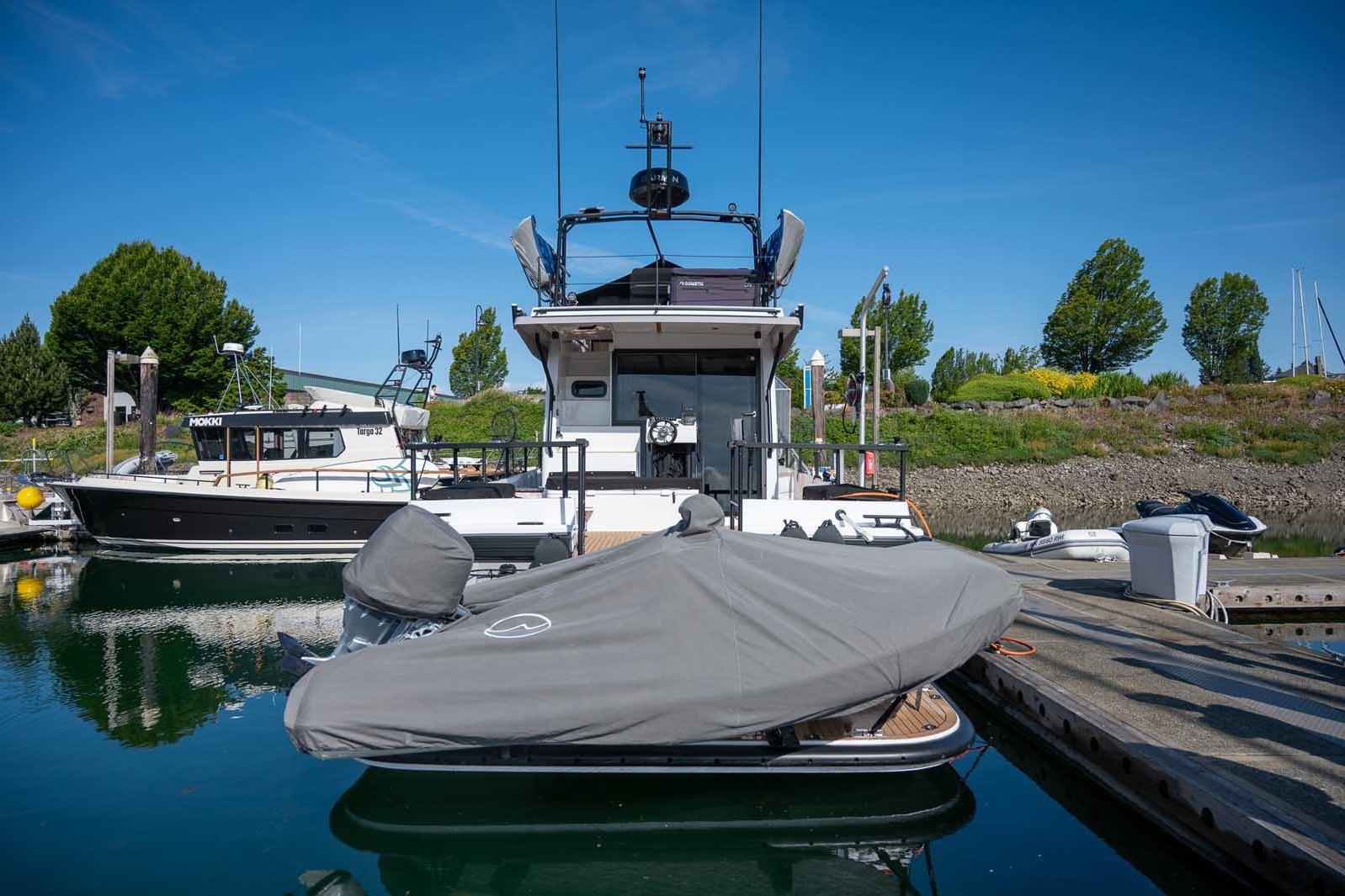 2025 Targa 46 yacht docked at marina, covered boat in foreground, clear blue sky.
