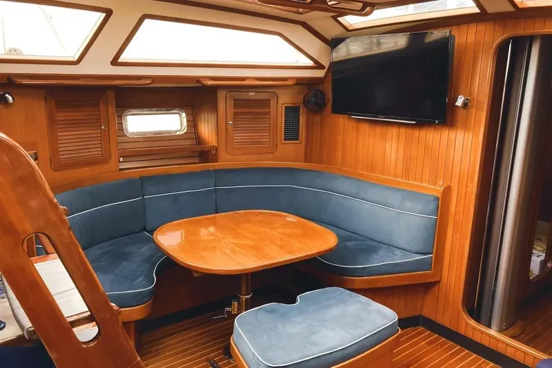 Violina Yacht Photos Pics Luxurious interior of a 1999 Hylas 54 yacht with wood paneling and blue seating.