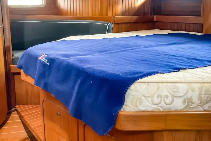 Violina Yacht Photos Pics Cozy cabin interior of 1999 Hylas 54 yacht with blue blanket on bed.