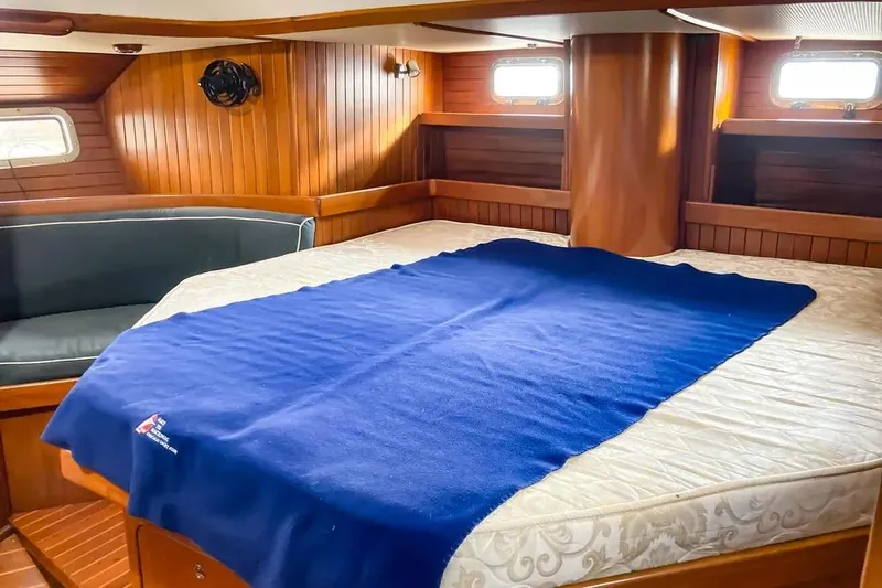 Violina Yacht Photos Pics Cozy cabin interior of 1999 Hylas 54 yacht with wooden paneling and blue blanket.