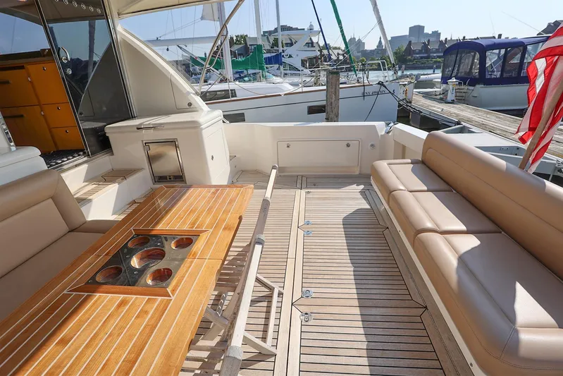  Yacht Photos Pics Luxurious 2016 Riviera 525 SUV yacht deck with seating and wooden table at marina.