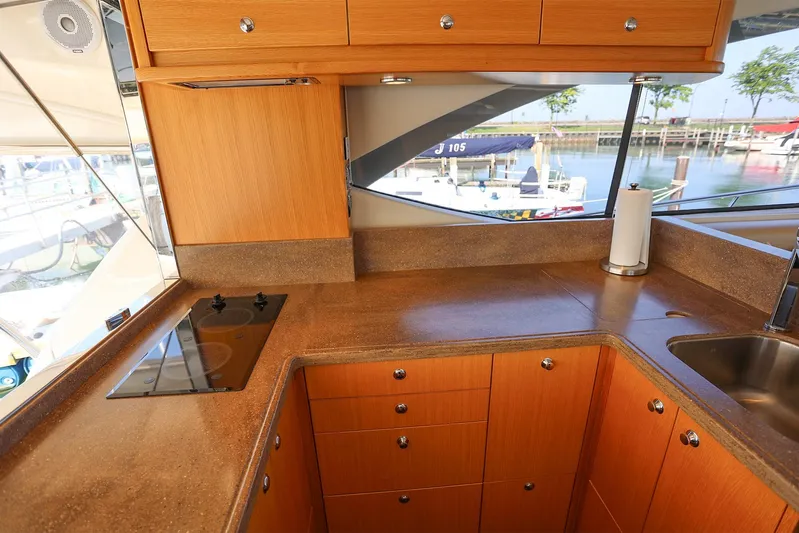  Yacht Photos Pics Interior of 2016 Riviera 525 SUV yacht kitchen with wooden cabinets and marina view.