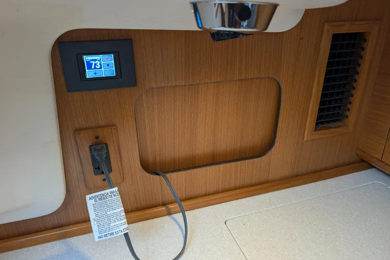 Uno Mas Yacht Photos Pics 2021 Catalina 315 interior with digital thermostat and power outlet on wooden panel.