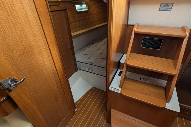 Uno Mas Yacht Photos Pics Interior of 2021 Catalina 315 sailboat with wooden steps and cozy sleeping area.