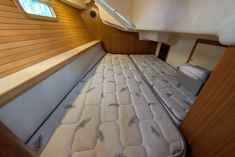 Uno Mas Yacht Photos Pics 2021 Catalina 315 yacht interior cabin with twin mattresses and wooden paneling.