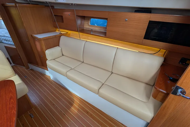 Uno Mas Yacht Photos Pics Interior of 2021 Catalina 315 yacht with beige leather sofa and wooden cabinetry.