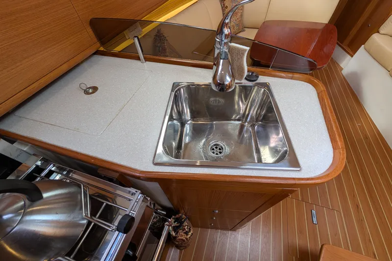 Uno Mas Yacht Photos Pics 2021 Catalina 315 yacht kitchen with stainless steel sink and wooden cabinetry.