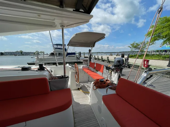 Artemis Yacht Photos Pics 2022 Excess 12 catamaran with red seating, docked at a marina under a blue sky.
