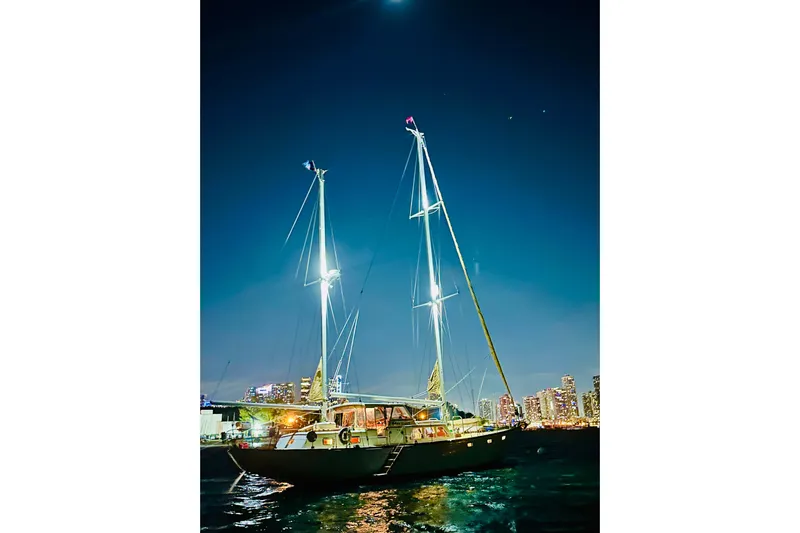 Scout (name Reserved) Yacht Photos Pics Sailboat "Alden Boothbay Explorer" 1971 at night, illuminated against city skyline.