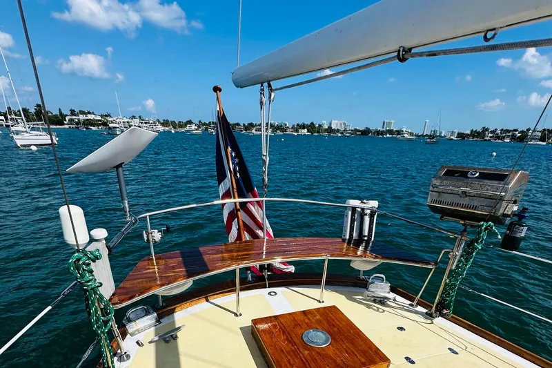 Scout (name Reserved) Yacht Photos Pics Alden Boothbay Explorer 1971 sailboat on serene blue waters, featuring a wooden deck and American flag.