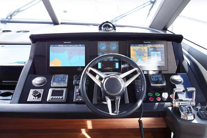  Yacht Photos Pics Control panel of a 2016 Princess 75 yacht with navigation screens and steering wheel.