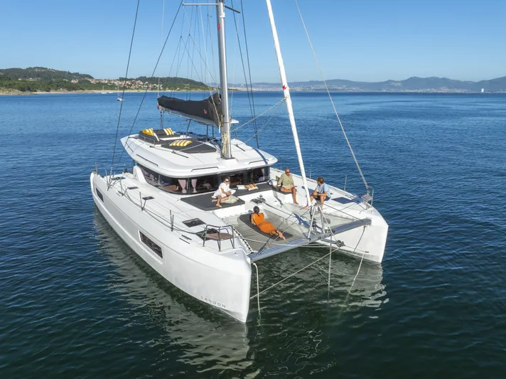  Yacht Photos Pics 2025 Lagoon 43 catamaran sailing on calm waters with people relaxing on deck.