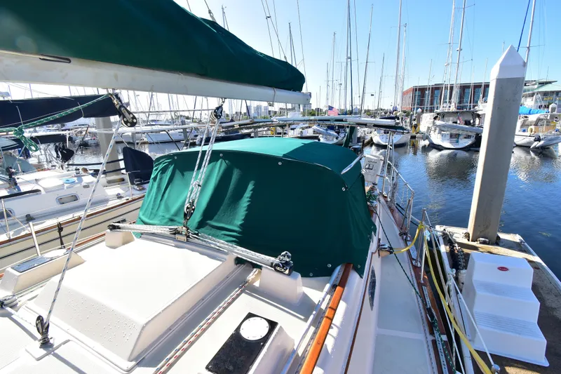 Shibumi Yacht Photos Pics 1995 Island Packet 37 sailboat docked at marina, featuring green canopy and rigging.