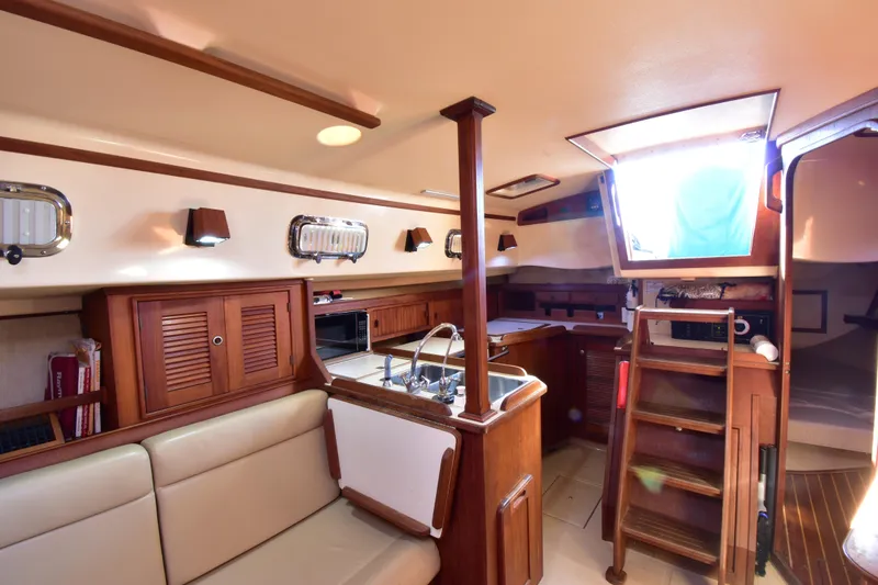 Shibumi Yacht Photos Pics Interior of 1995 Island Packet 37 sailboat with wood finishes and compact kitchen area.