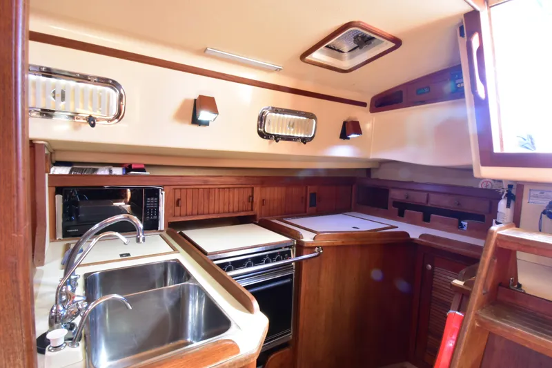 Shibumi Yacht Photos Pics Cozy 1995 Island Packet 37 yacht kitchen with sink, stove, and wooden cabinetry.