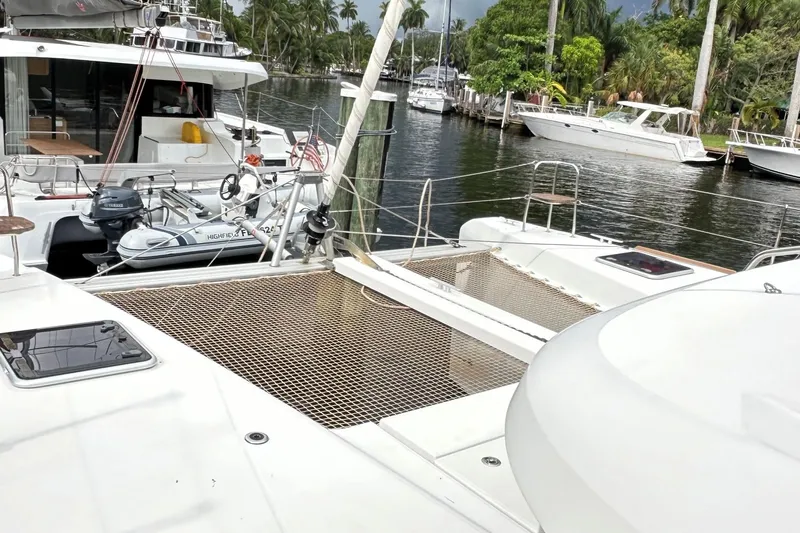 Keola Yacht Photos Pics 2022 Lagoon 40 catamaran docked with dinghy, surrounded by lush greenery and other boats.