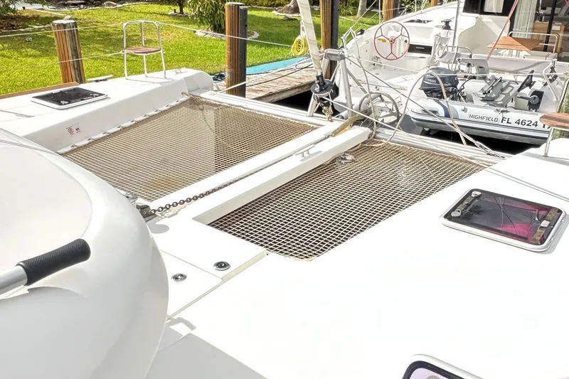 Keola Yacht Photos Pics 2022 Lagoon 40 catamaran deck with netting and docked boat in background.