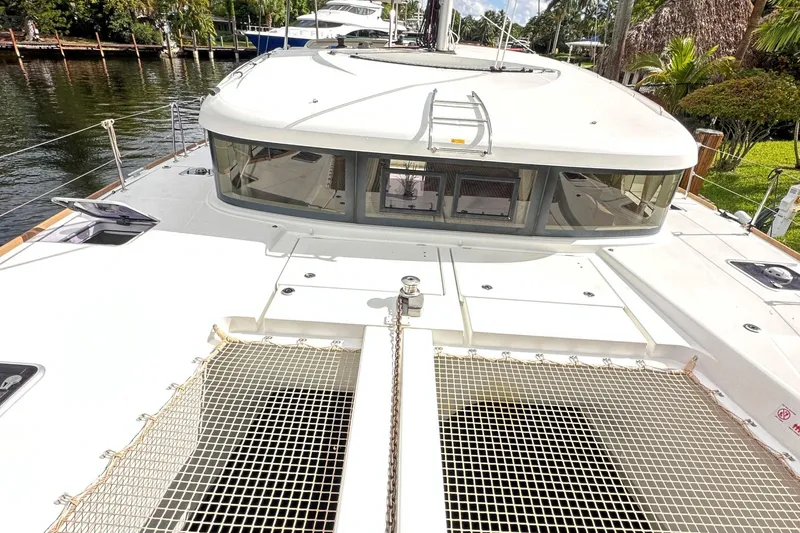 Keola Yacht Photos Pics 2022 Lagoon 40 catamaran deck with netting, docked by lush greenery.