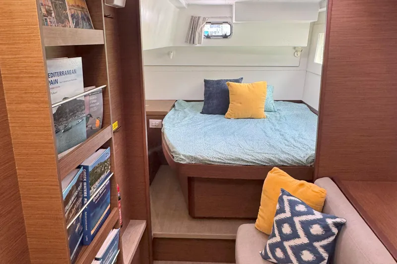 Keola Yacht Photos Pics Cozy cabin interior of 2022 Lagoon 40 catamaran with bed, cushions, and bookshelf.