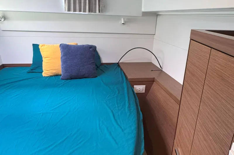 Keola Yacht Photos Pics Cozy cabin interior of 2022 Lagoon 40 catamaran with colorful pillows and wooden cabinetry.