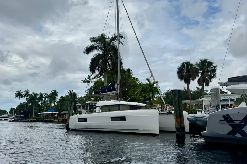 Keola Yacht Photos Pics 2022 Lagoon 40 catamaran docked by palm trees under cloudy sky.