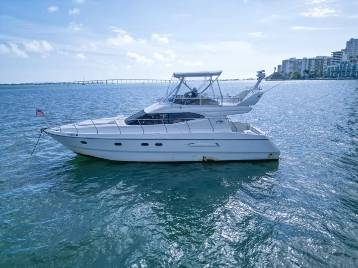  Yacht Photos Pics Azimut 43 yacht from 1997 on calm waters with cityscape background.