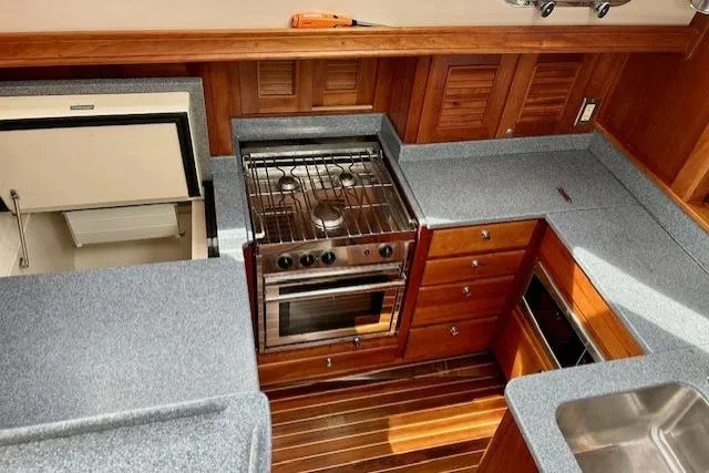 Blue Moon Yacht Photos Pics 2016 Gozzard 41 RC yacht kitchen with stove, fridge, and wooden cabinetry.