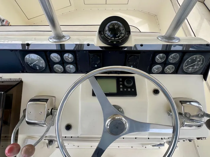 White Shark Yacht Photos Pics Helm of 1988 Hatteras 48 Convertible with steering wheel, gauges, and controls.